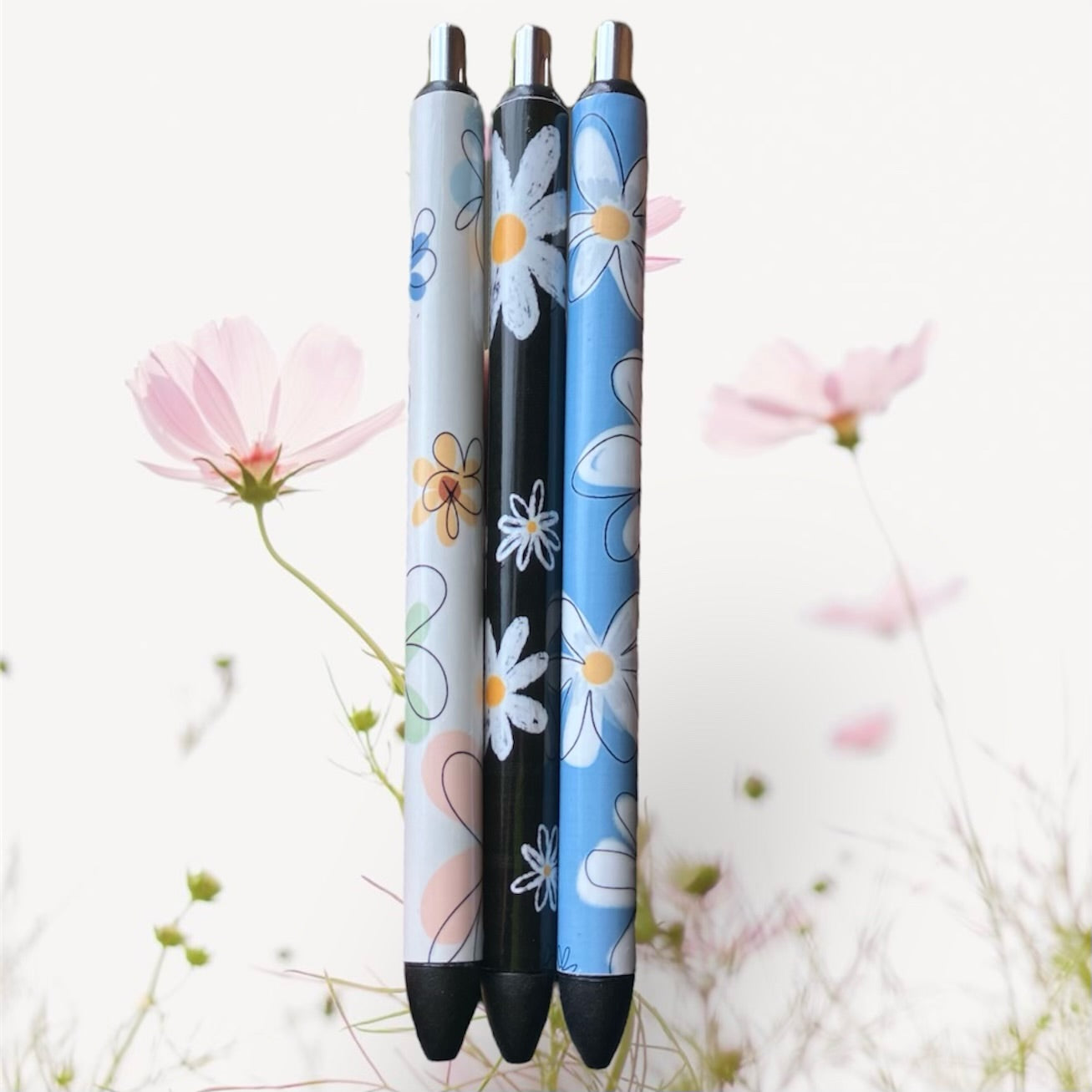 Photo of three flower print pens with a light flower background 